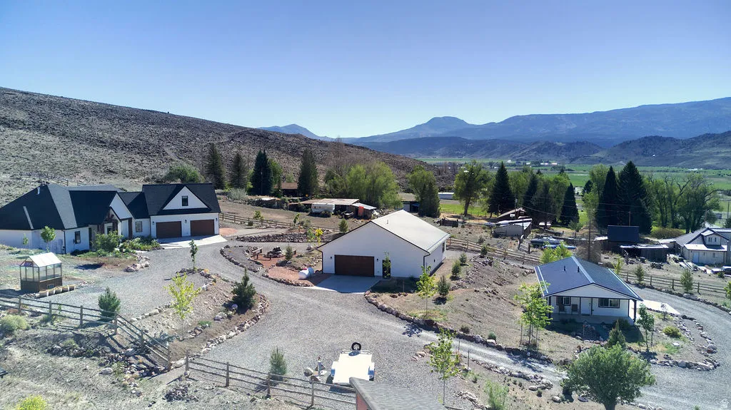 Expansive gravel driveway winding through a sloped property featuring three distinct residential structures
