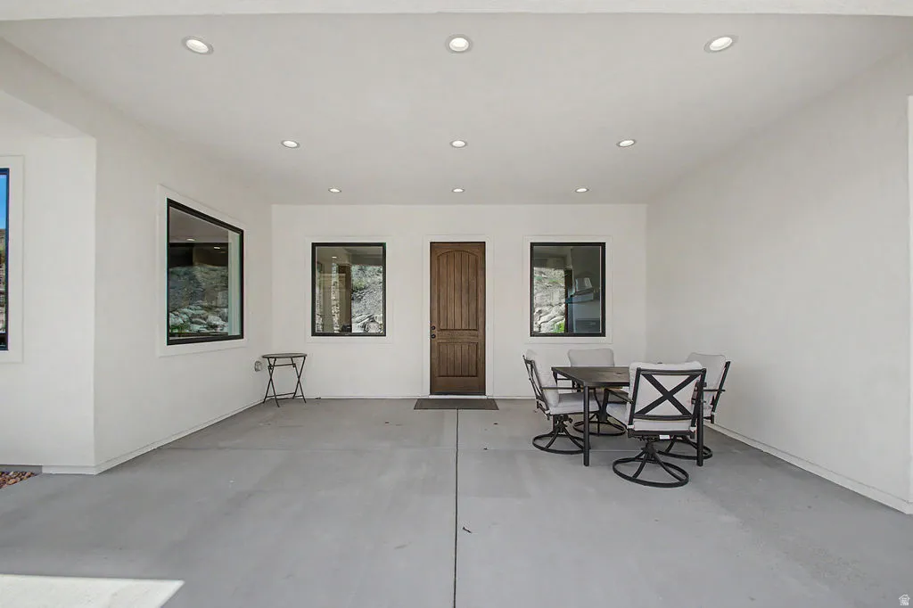 Covered patio with recessed lighting, a wood-finish entry door, and contemporary black-framed windows