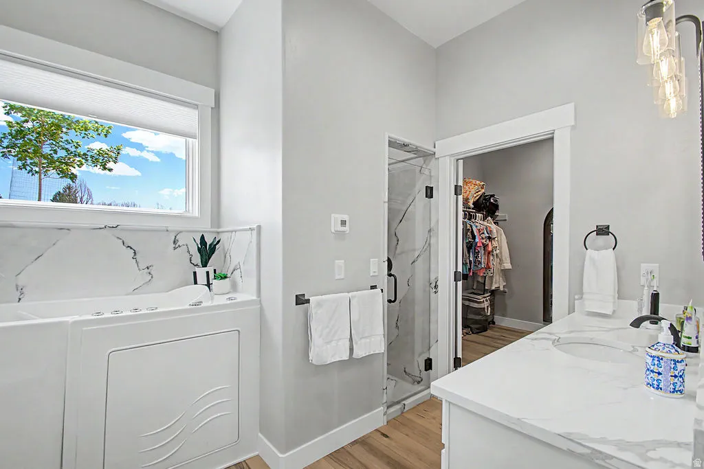 Contemporary bathroom featuring a walk-in tub with a tiled surround, a glass-enclosed shower with tiled walls, and a vanity with a white countertop and integrated sink