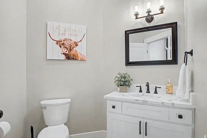 1/2 bath Vanity area featuring a crisp white cabinet with black hardware, quartz countertop, and a oval sink with a matte black faucet
