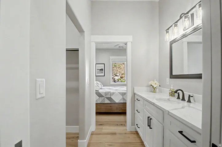 Vanity with white cabinetry and black hardware, quartz countertop, single basin sink, and oil-rubbed bronze faucet