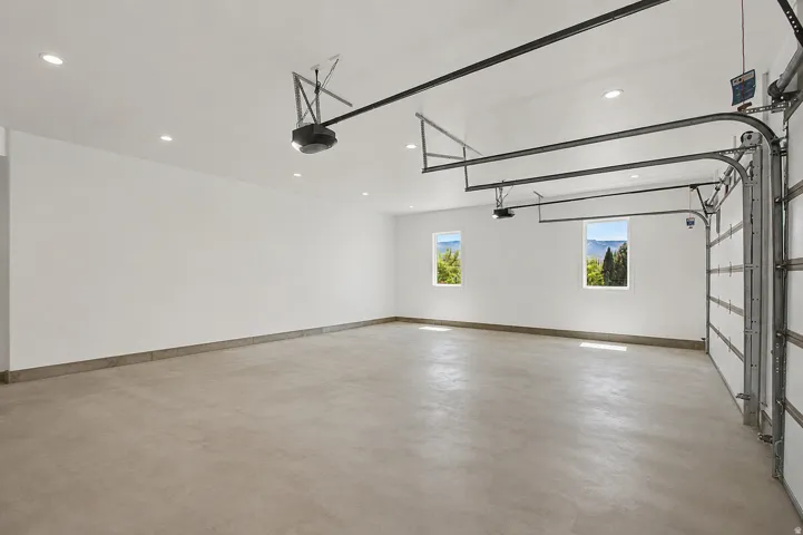Spacious garage featuring a concrete floor, two windows providing natural light, recessed ceiling lighting.
