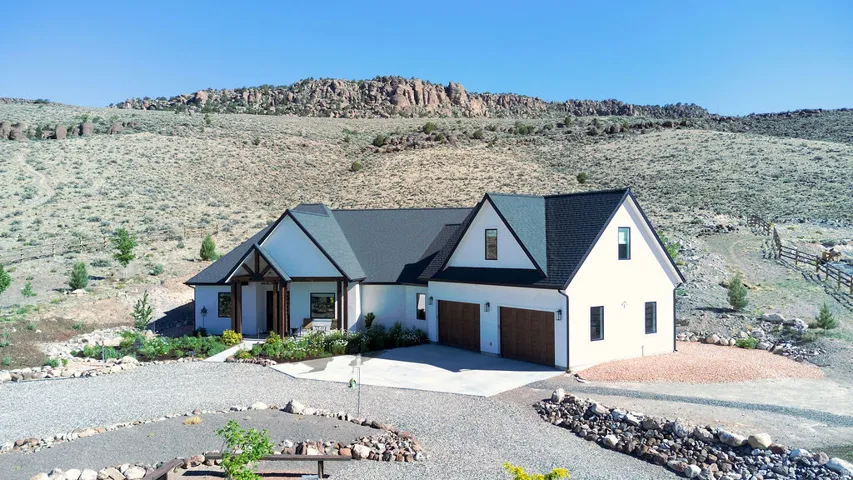 Contemporary farmhouse architecture featuring a dark shingle roof, white stucco , and a prominent wood-clad entry porch