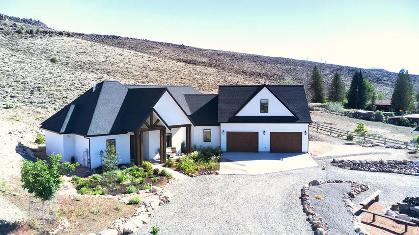Contemporary white stucco exterior with a dark shingle roof, featuring a covered entry with timber accents