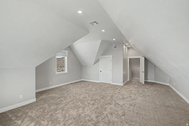 Bonus Room Spacious room featuring sloped ceilings, recessed lighting, neutral-toned carpet, a window with mountain scenery, and two windows with mountain and valley scenery.