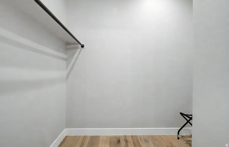 Walk-in closet featuring a single hanging rod, hardwood flooring, and white baseboards