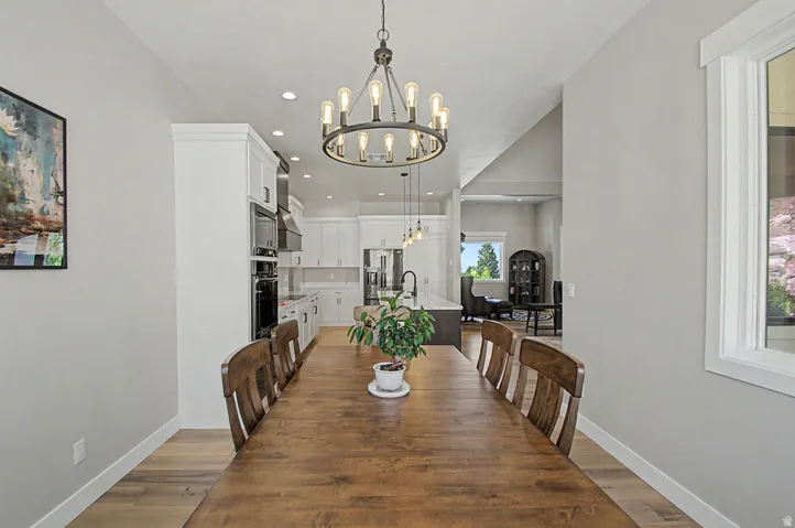 Spacious dining area featuring Hallmark Orris Maple  flooring and a contemporary chandelier