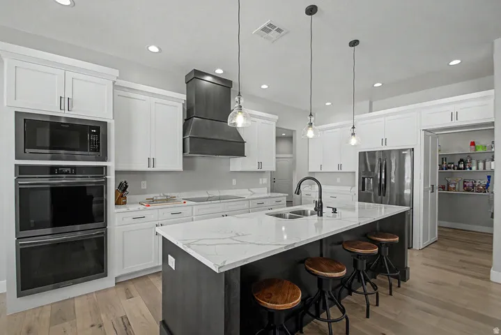Bright kitchen featuring an expansive center island with seating, a double basin sink, and pendant lighting
