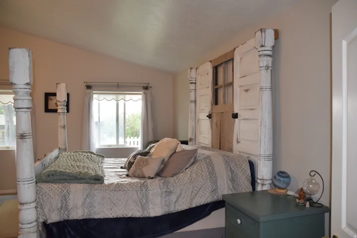 Vaulted ceiling bedroom with a custom built-in headboard featuring repurposed door panels
