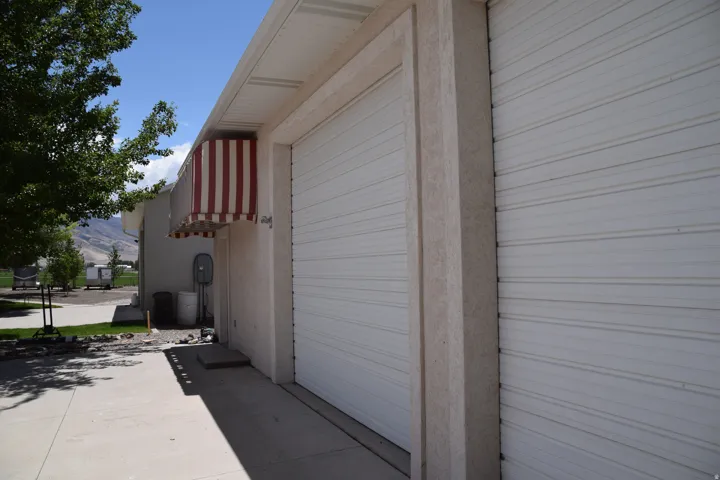 Two white overhead garage doors with textured stucco columns