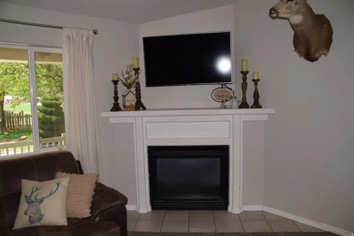 Corner fireplace with a white mantel and hearth, featuring a built-in electric insert