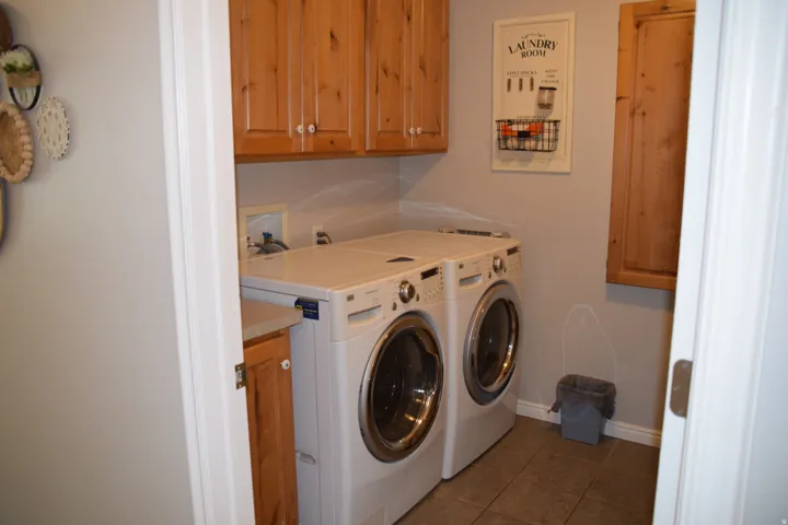 Dedicated laundry space featuring wood cabinetry, a light-toned countertop, and tile flooring