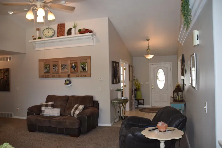 Vaulted ceiling with an overhead fan light fixture in the living area, featuring a decorative wall shelf