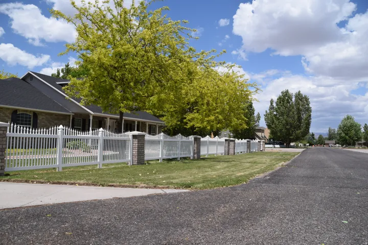 Brick-clad exterior with a dark shingle roof, complemented by a white picket fence with brick pillars