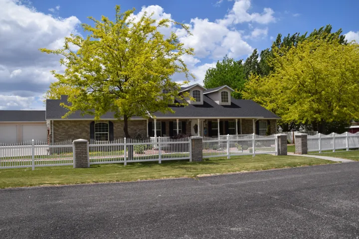 Classic brick exterior residence featuring a dark shingle roof and a covered front porch