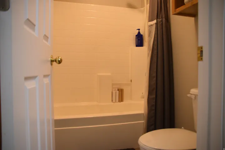 Bathroom featuring a white subway tile tub surround, built-in shelving, and a white bathtub