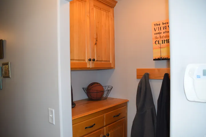 Custom wood-finish cabinetry featuring black hardware and integrated coat rack