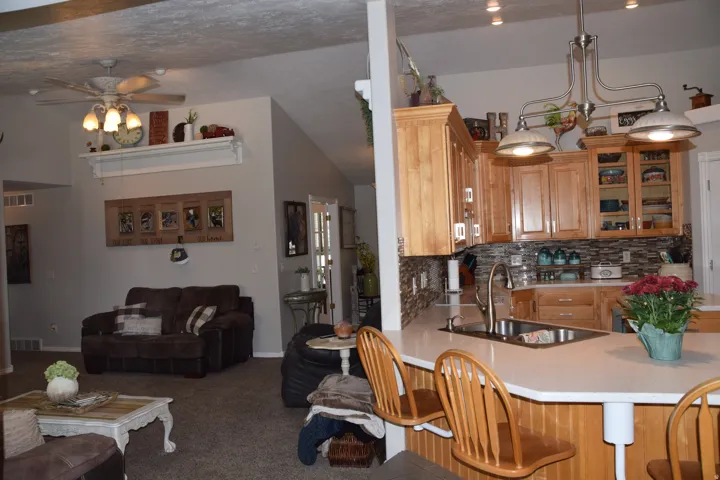 Kitchen featuring light wood cabinetry, a tiled backsplash, and a breakfast bar with built-in seating