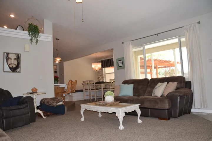Open-concept living area with vaulted ceilings and carpet flooring