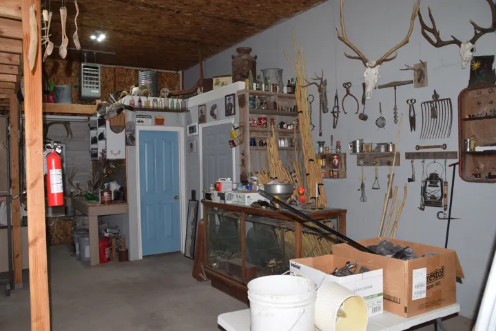 Utility room featuring a light blue door, concrete flooring, exposed wood beam, and a wood-paneled ceiling