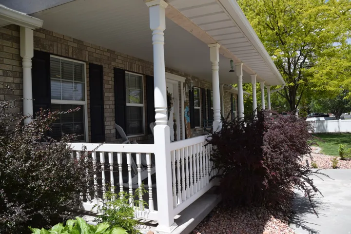 Brick facade with a covered front porch featuring white columns and railing