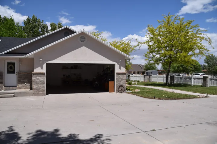 Two-car garage with a wide concrete driveway, stucco exterior, and brick accents