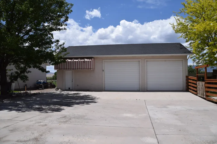 Two-car garage with white roll-up doors, a separate entry door, and a striped awning
