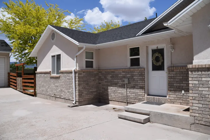 Exterior facade featuring light-toned stucco and brick accents