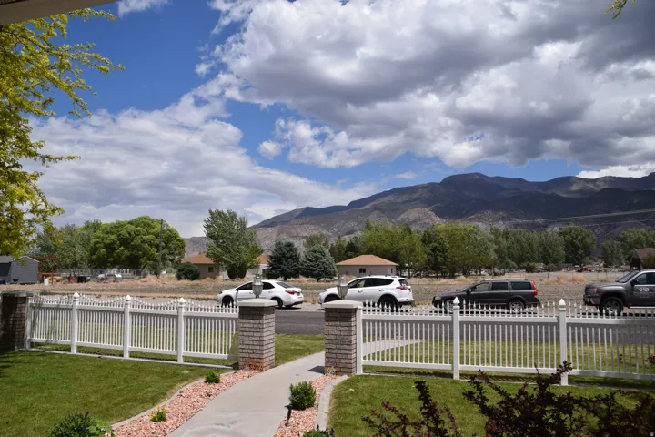 Manicured front yard with a white picket fence and brick pillars framing the entrance