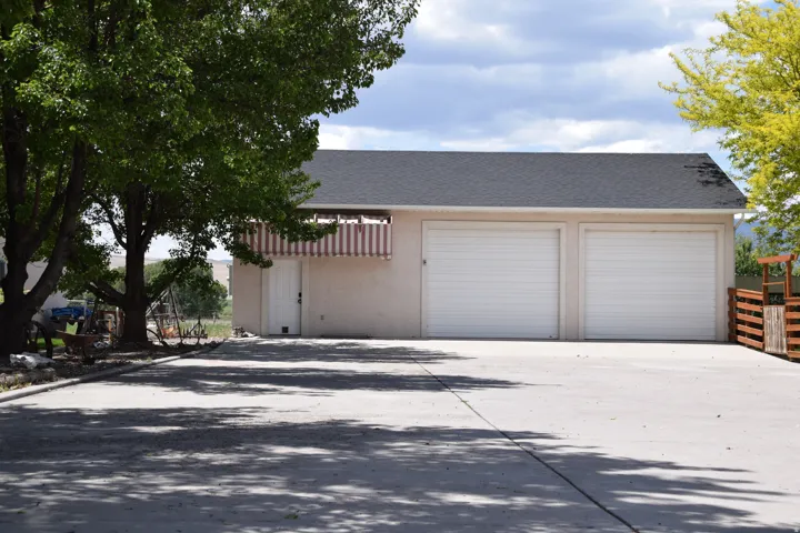 Two-car garage with white roll-up doors, a dark shingle roof, and stucco exterior