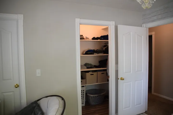 Organized closet storage featuring multiple shelving units and wood-finish flooring