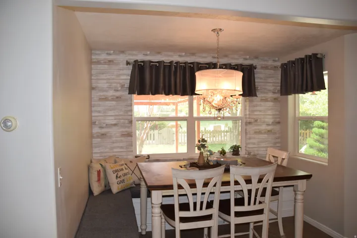 Dining area featuring a crystal chandelier, wood-finish accent wall, and multiple windows
