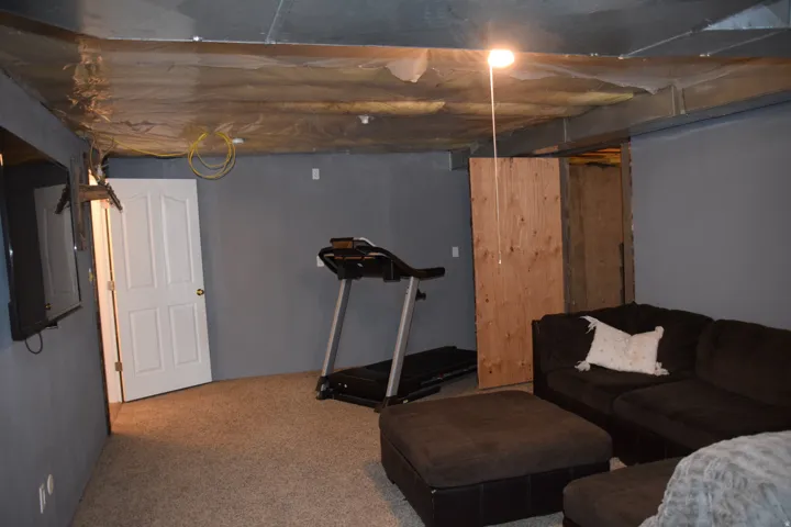 Carpeted room with painted gray walls and an exposed ceiling