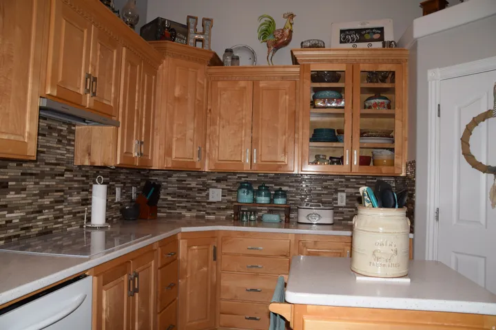 Kitchen featuring natural wood cabinetry, light-toned countertops, and a mosaic tile backsplash