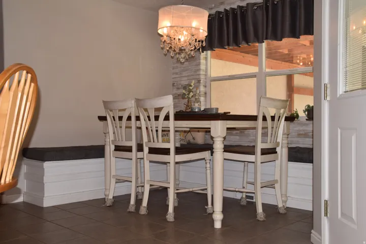 Dining area featuring tile flooring, a window with a valance, and a built-in bench seating