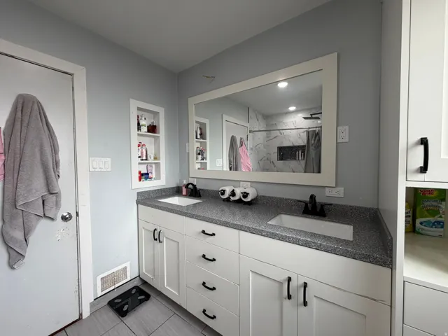 Double vanity with white shaker-style cabinetry and a speckled dark countertop