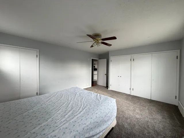 Spacious room with plush carpet flooring, light gray wall paint, and multiple bi-fold closet doors providing ample storage