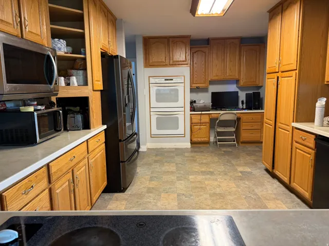 Kitchen featuring wood cabinetry, built-in double ovens, and a dedicated desk area