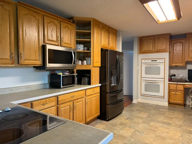 Kitchen featuring wood cabinetry, stone-look countertops, and a black refrigerator