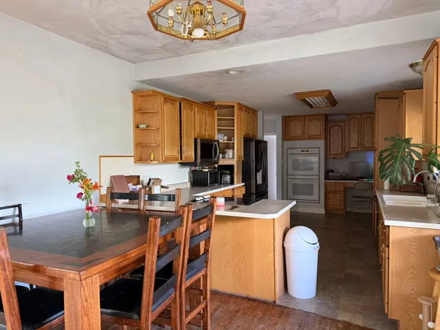 Kitchen and dining area featuring wood-finish cabinetry, light-toned countertops, and built-in double ovens
