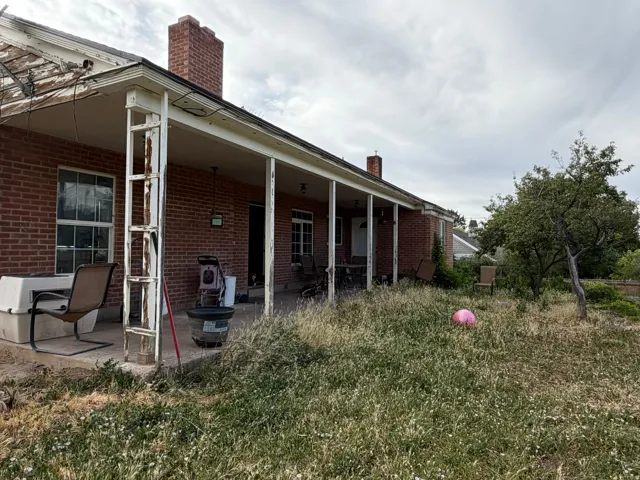 Brick exterior featuring a covered patio, multiple windows, and a chimney