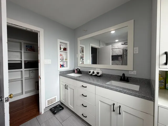 Bathroom featuring a double vanity with white cabinetry, dark speckled countertops, and undermount sinks