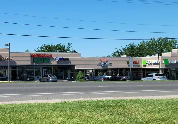 Commercial strip center featuring multiple storefronts with large display windows, consistent exterior facade, and on-site parking