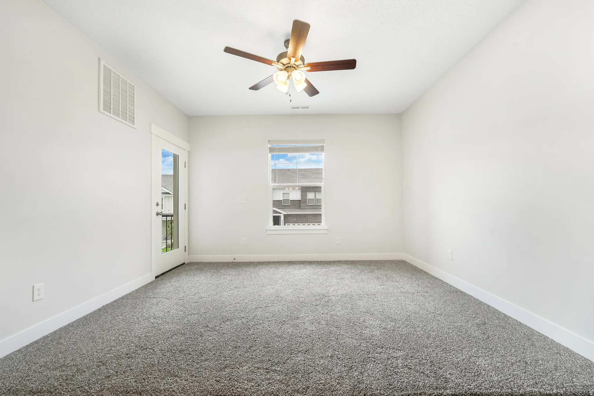 Spacious room featuring neutral carpeting, white baseboards, and a ceiling fan with integrated lighting
