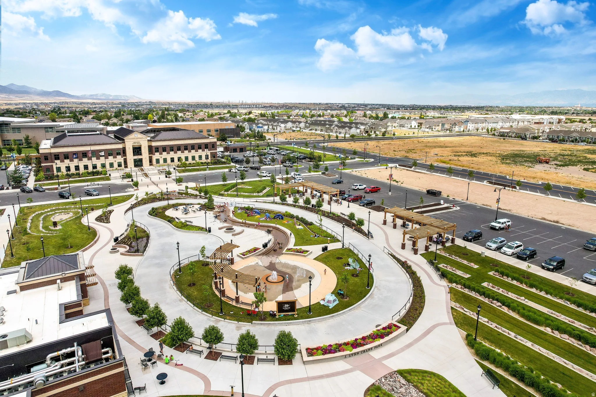 Expansive community green space featuring winding pathways, landscaped garden beds, and multiple shaded pergola structures