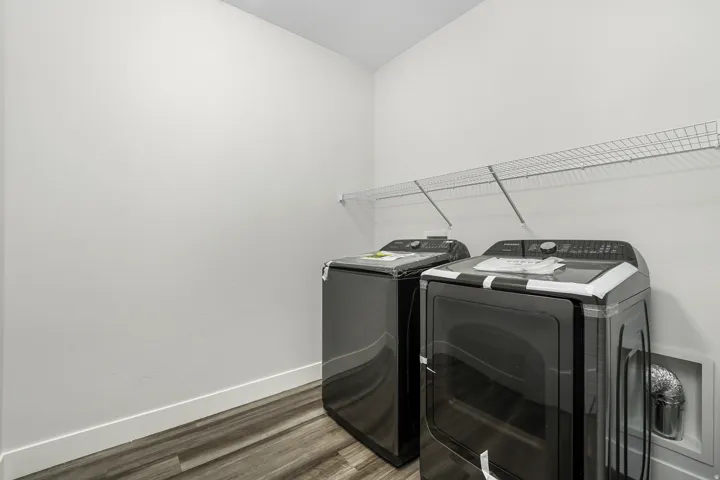 Dedicated laundry space featuring a wire shelf for storage, light-toned walls, and wood-finish flooring
