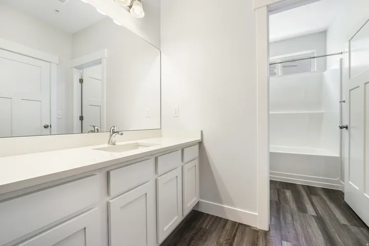 Bathroom featuring a vanity with white cabinetry, a light-toned countertop, and an integrated sink with a chrome faucet
