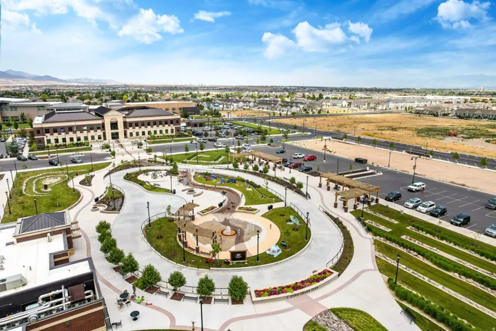 Expansive community green space featuring winding pathways, landscaped garden beds, and multiple shaded pergola structures