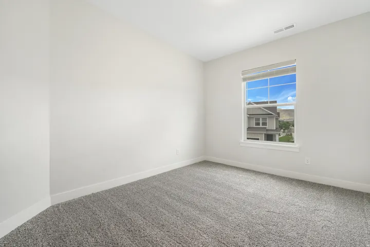 Room featuring a window with a roller shade, light gray carpeting, and white baseboards