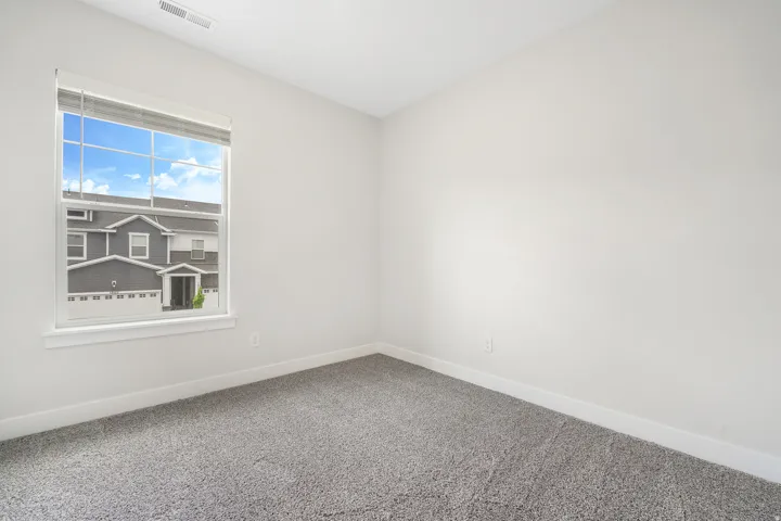 Neutral gray carpet flooring, white painted walls, and a large window with white trim